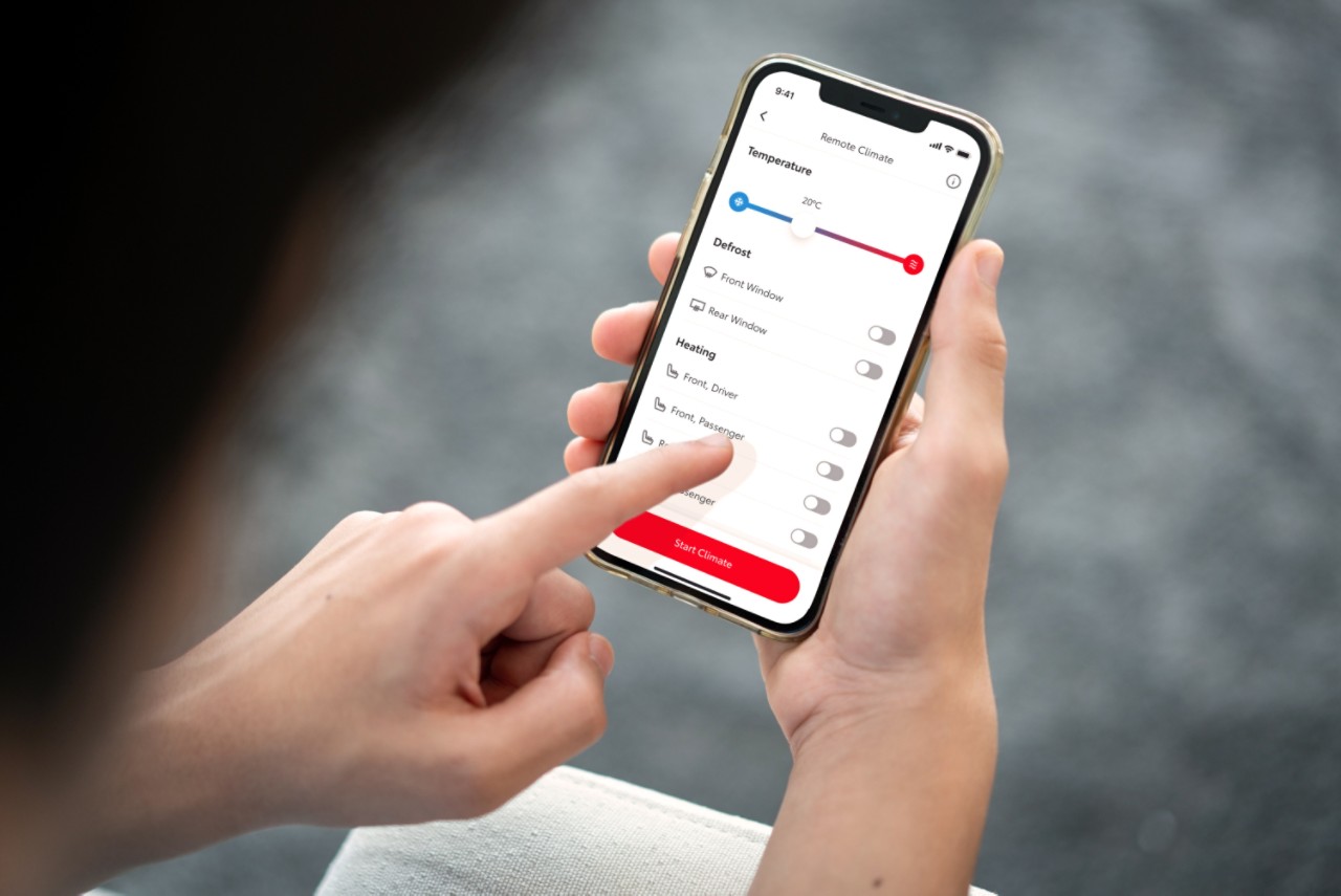 Osoba drži pametni telefon na kojem je prikazana aplikacija MyToyota. Njihova leva ruka dodiruje ekran da bi daljinski unapred postavila kontrolu klime u svom automobilu.